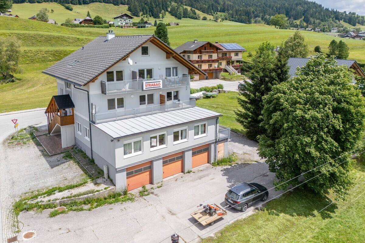 Luftaufnahme des Gebäudes mit Balkonen, Garagen und der weiten grünen Landschaft.