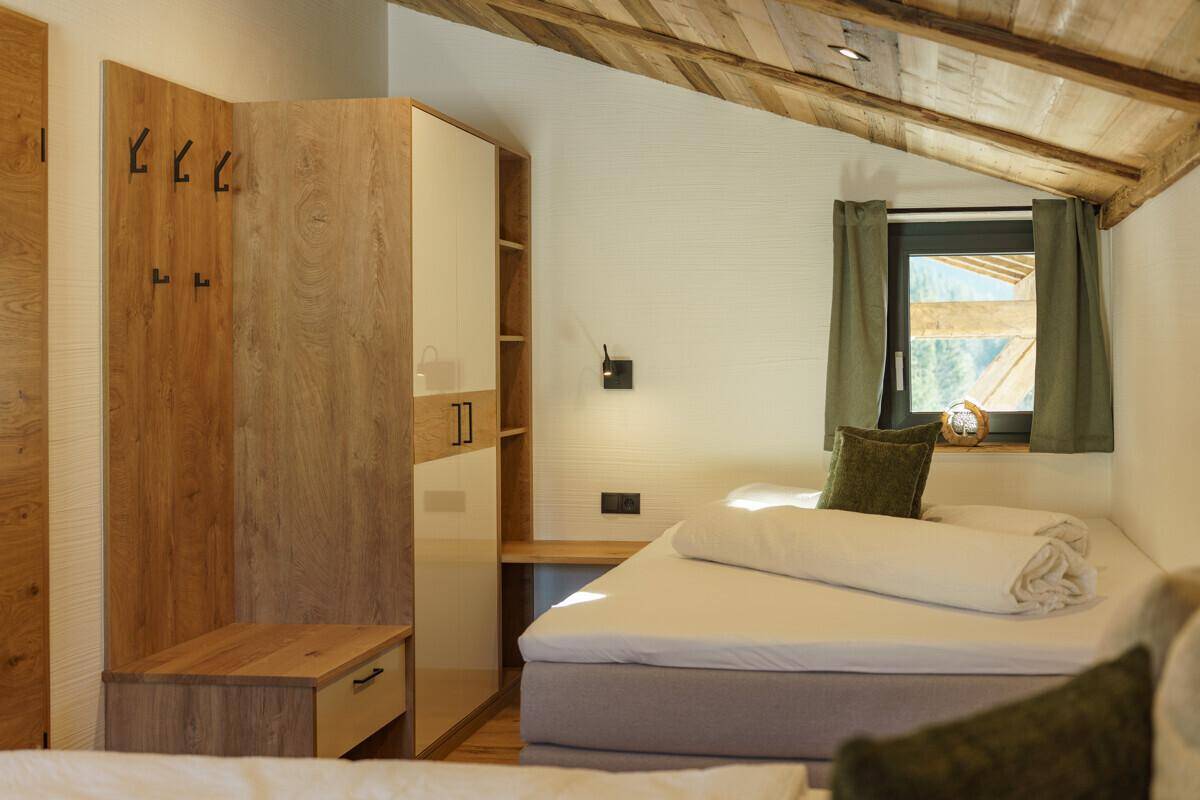 Gemütliches Schlafzimmer mit Holzbalkendecke, Einbauschrank und Fenster mit Bergblick.