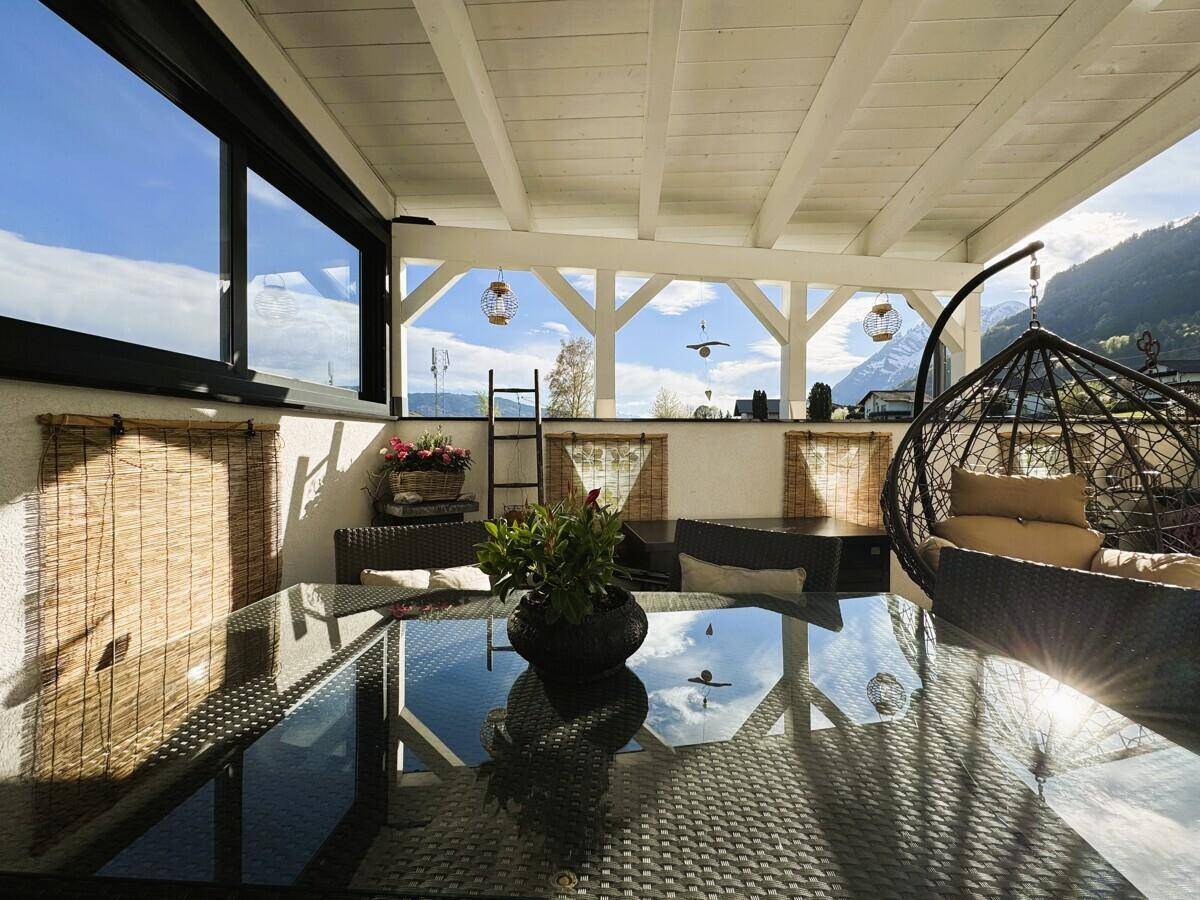 Heller Terrassenbereich mit Glasplatte auf dem Tisch und weitem Blick in die Natur.
