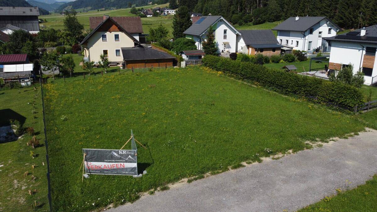 Luftaufnahme eines zum Verkauf stehenden Grundstücks umgeben von Wohnhäusern in ländlicher Umgebung.