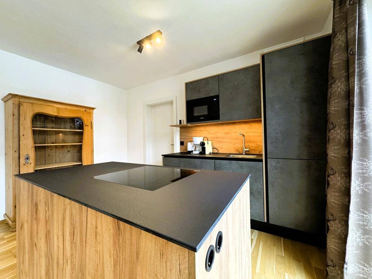 Offener Wohn- und Essbereich mit moderner Küche, Holzakzenten und traditionellem Schrank.