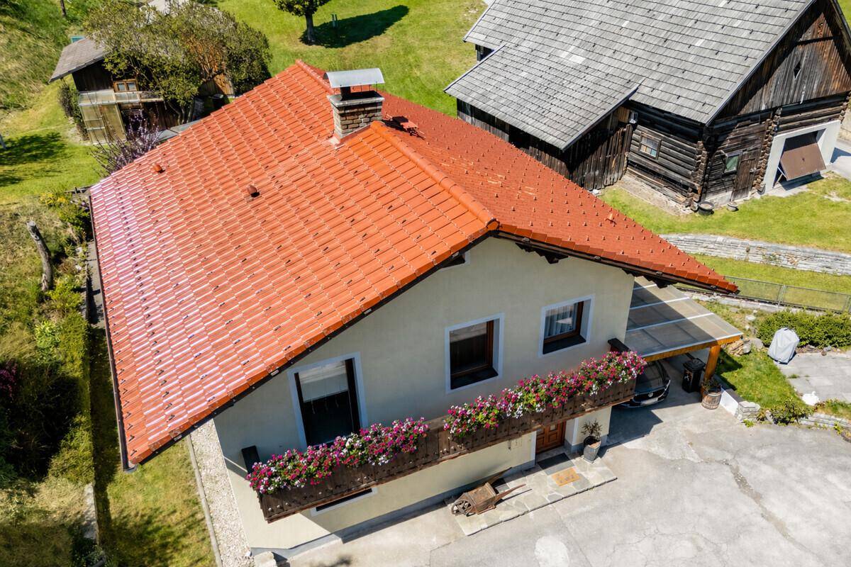 Luftaufnahme des Hauses mit rotem Ziegeldach und umliegender grüner Landschaft.