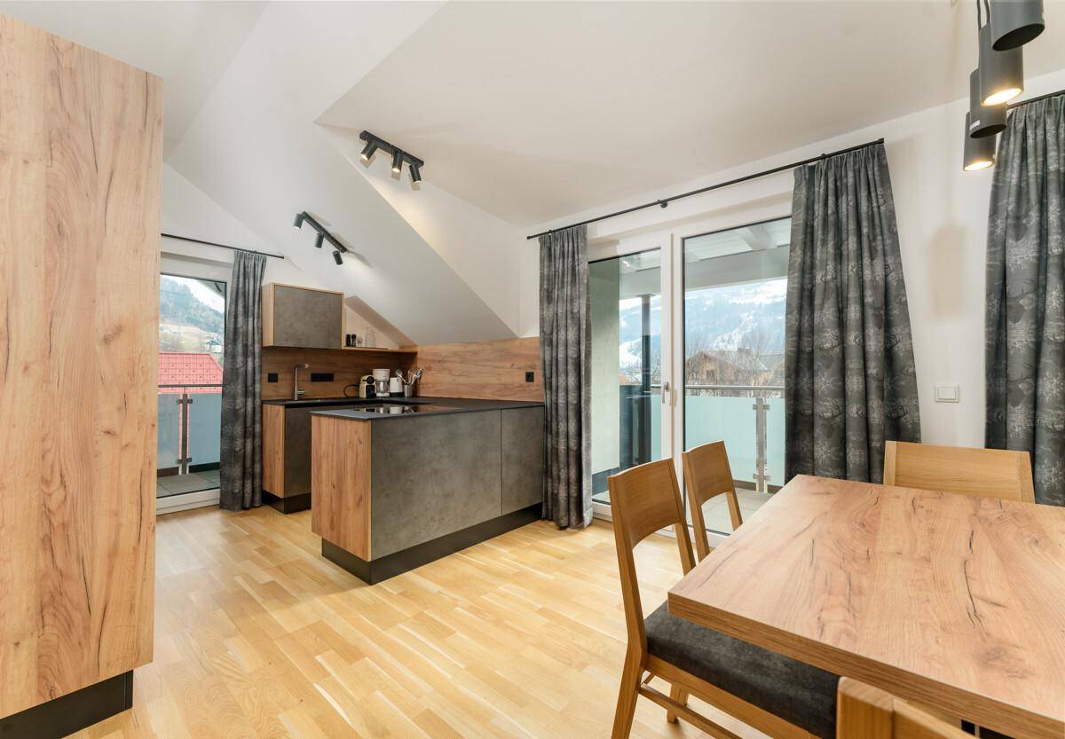Offene Küche mit Essbereich, modernen Geräten und Zugang zu einem sonnigen Balkon.