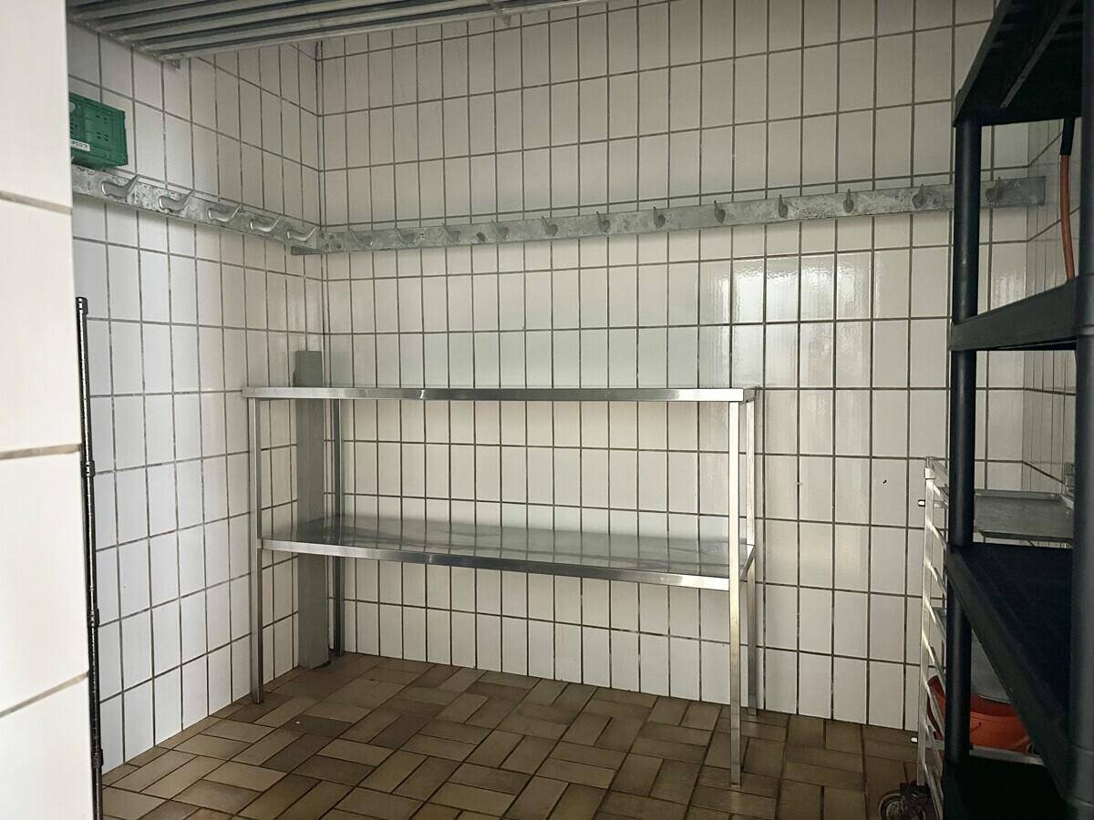 Einfacher Lagerraum mit weißen Fliesenwänden und praktischen Metallregalen für die Aufbewahrung.