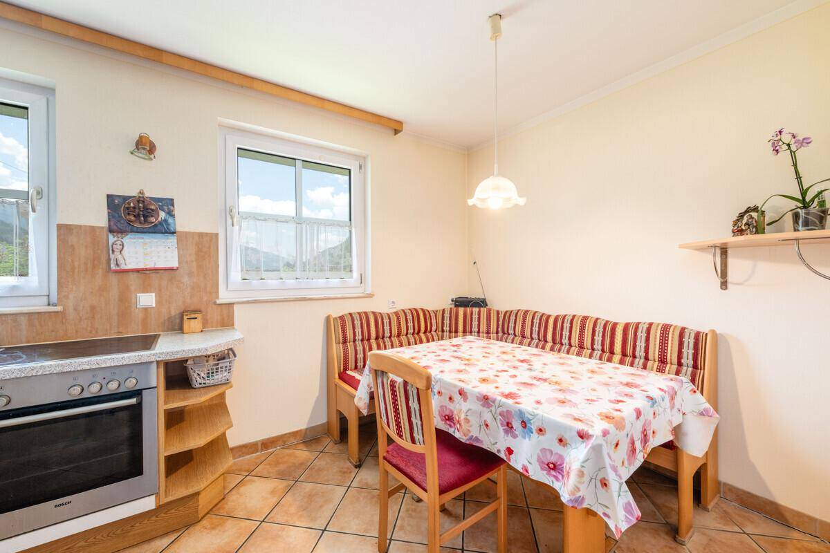 Traditionelle Küche mit rustikaler Eckbank, Esstisch und Bergblick durch das Fenster.