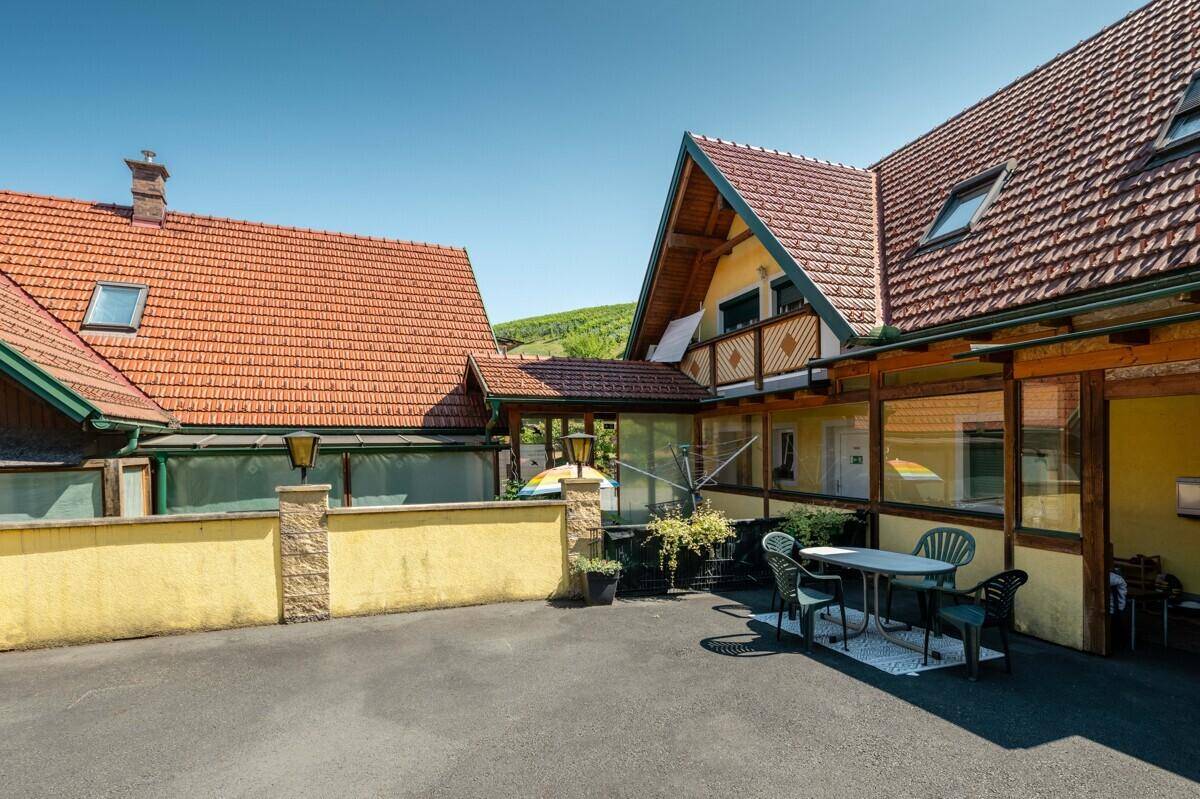 Gepflasterter Innenhof mit Sitzgelegenheiten und Blick auf die umliegenden Gebäude und Dächer.