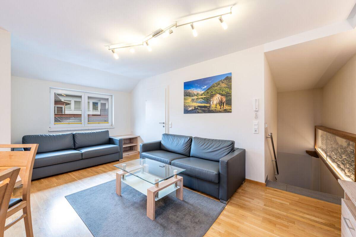 Heller Wohnbereich mit zwei bequemen Sofas, Couchtisch und Blick auf den Treppenabgang.