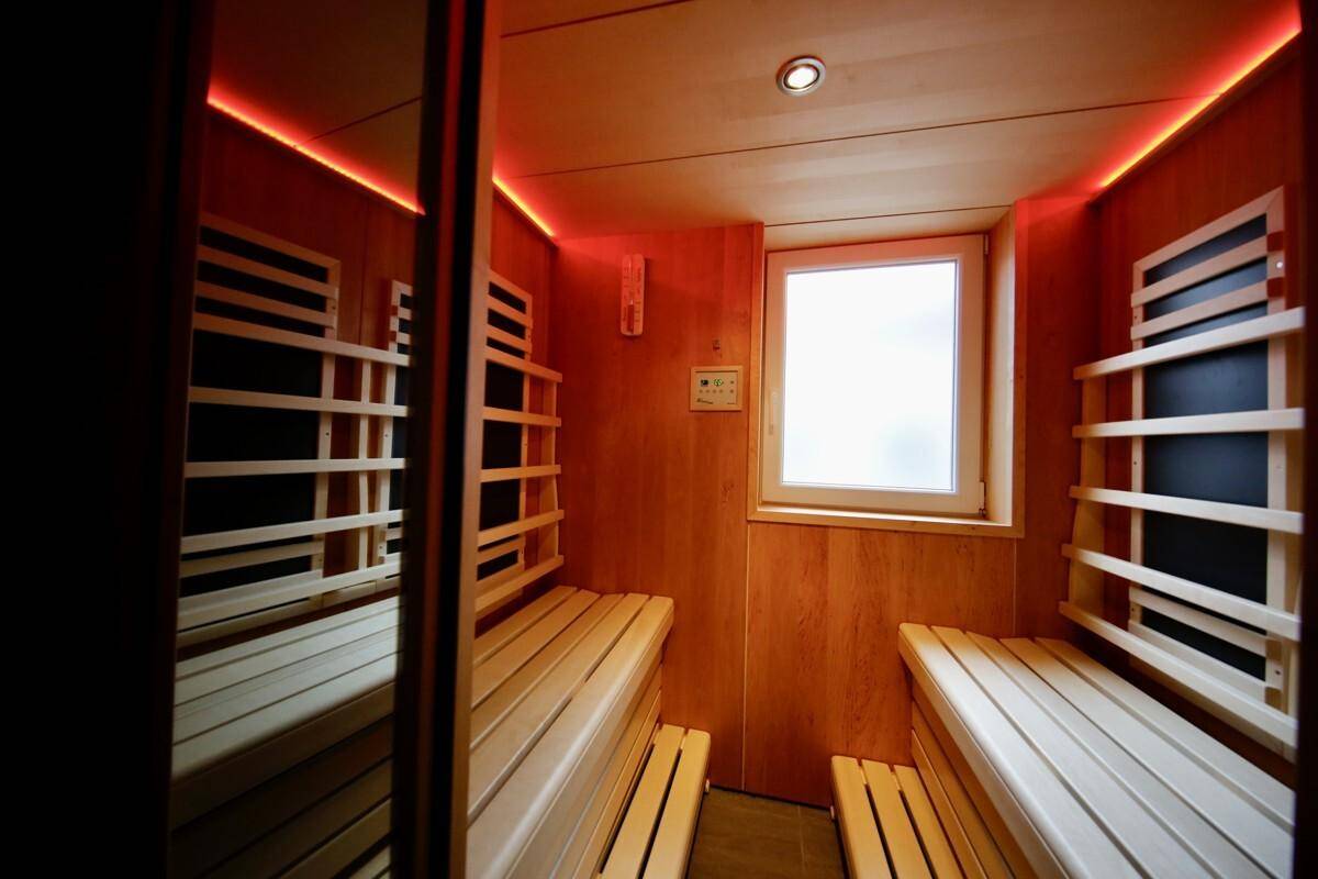 Innenansicht der Sauna mit Holzbänken, Fenster und indirekter Beleuchtung für entspannende Momente.