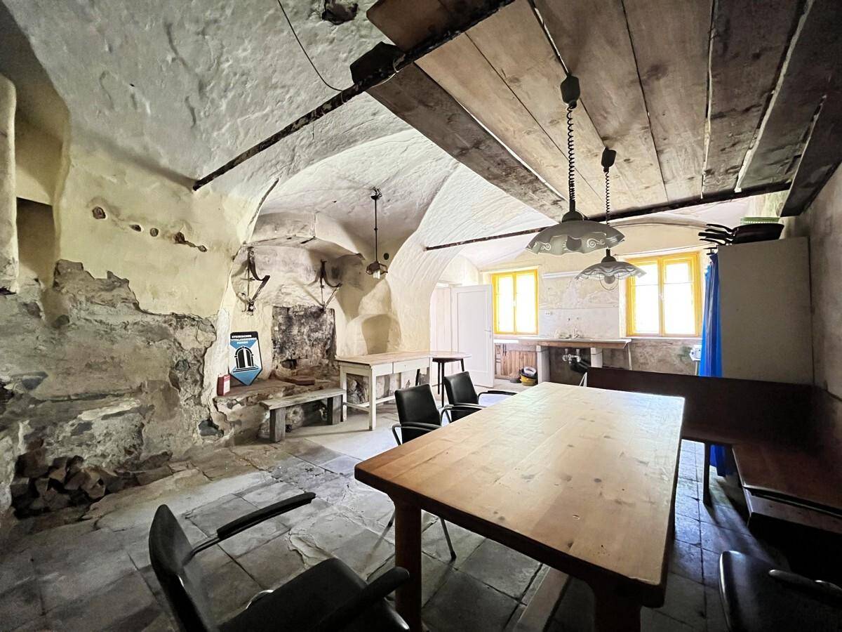 Historische Küche mit Gewölbedecke, Holztisch und Blick auf einfache Fenster.