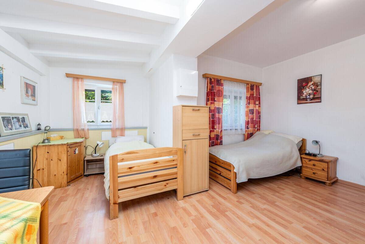 Helles Schlafzimmer mit zwei Einzelbetten, Holzboden und sichtbaren Deckenbalken, freundlich eingerichtet.