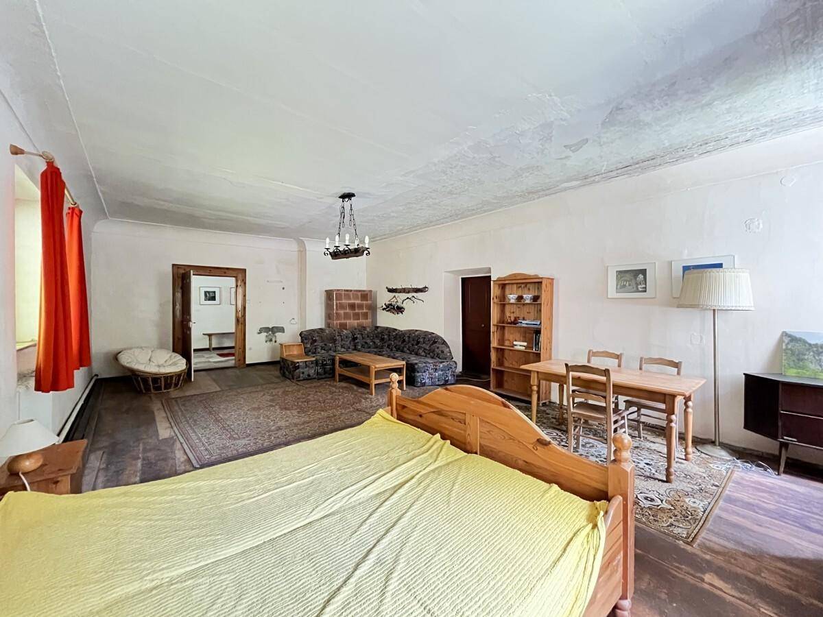 Großer Wohn- und Schlafbereich mit Holzboden, traditionellen Möbeln und Teppich.