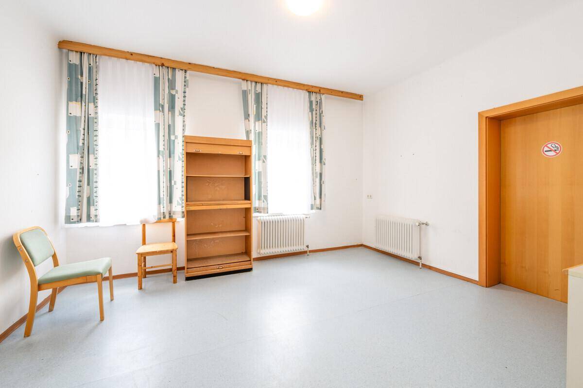 Geräumiges Zimmer mit Laminatboden, hellen Wänden und mehreren Fenstern.