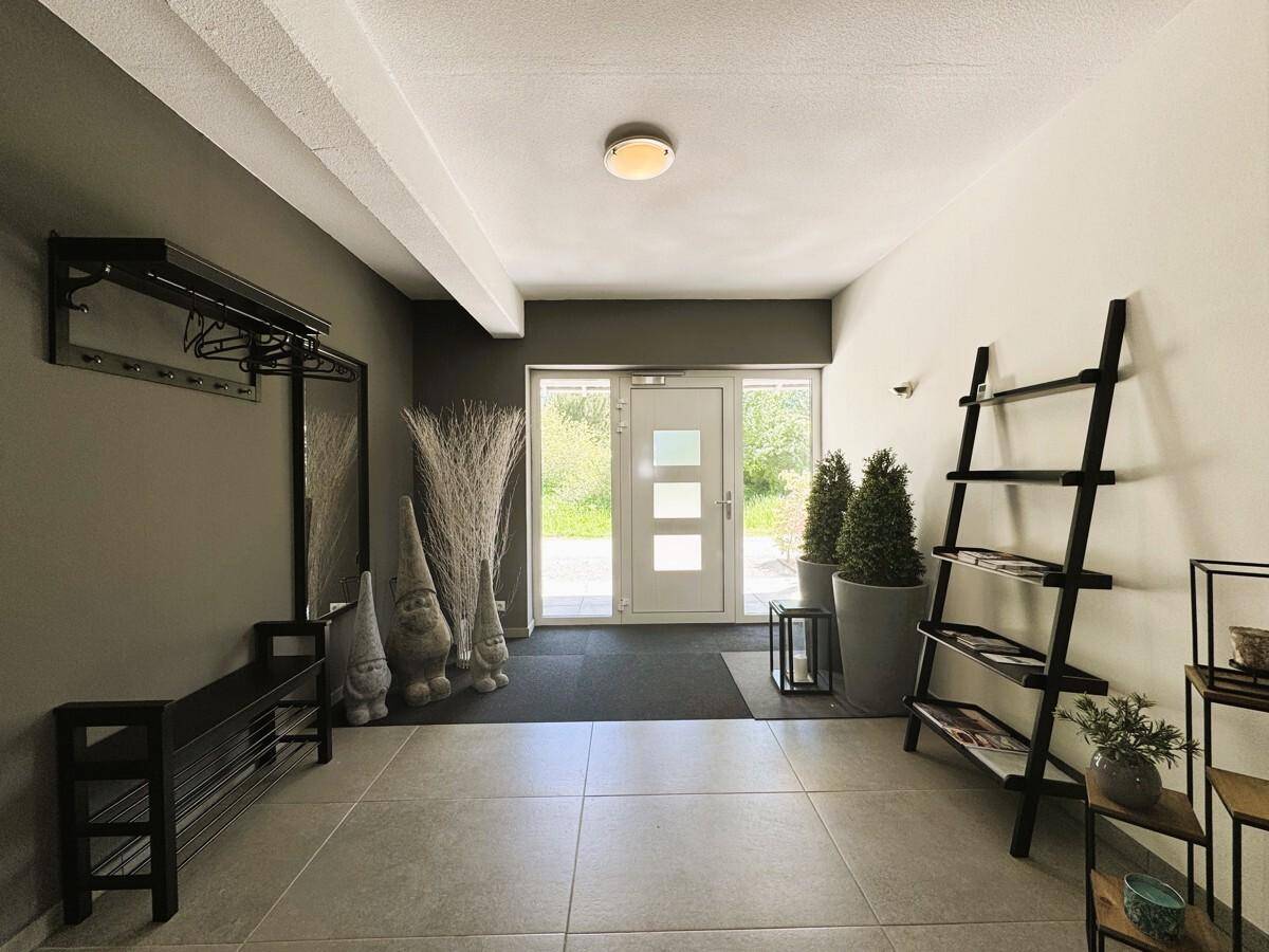 Heller Eingangsbereich mit Garderobe, Spiegel und Zugang zum Außenbereich.