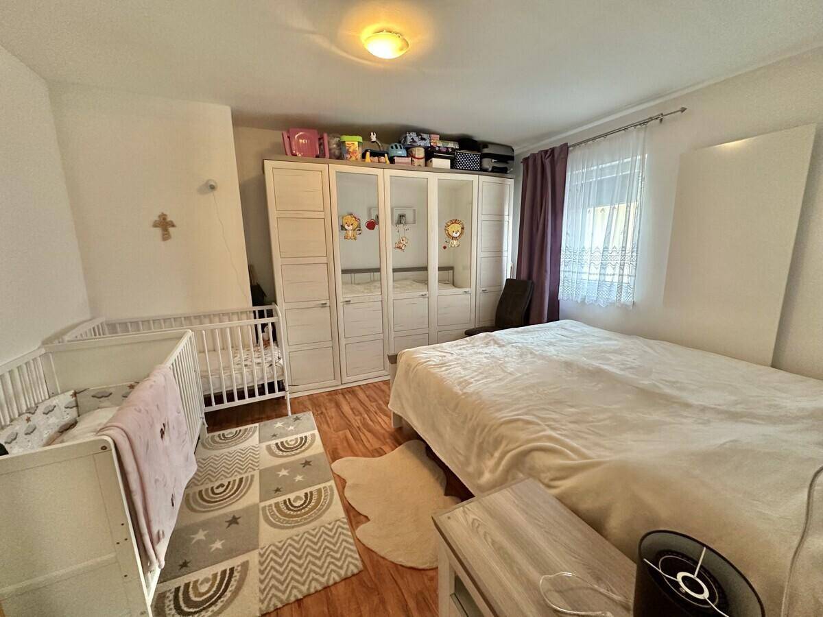 Schlafzimmer mit Doppelbett, Babybett und großem Kleiderschrank.