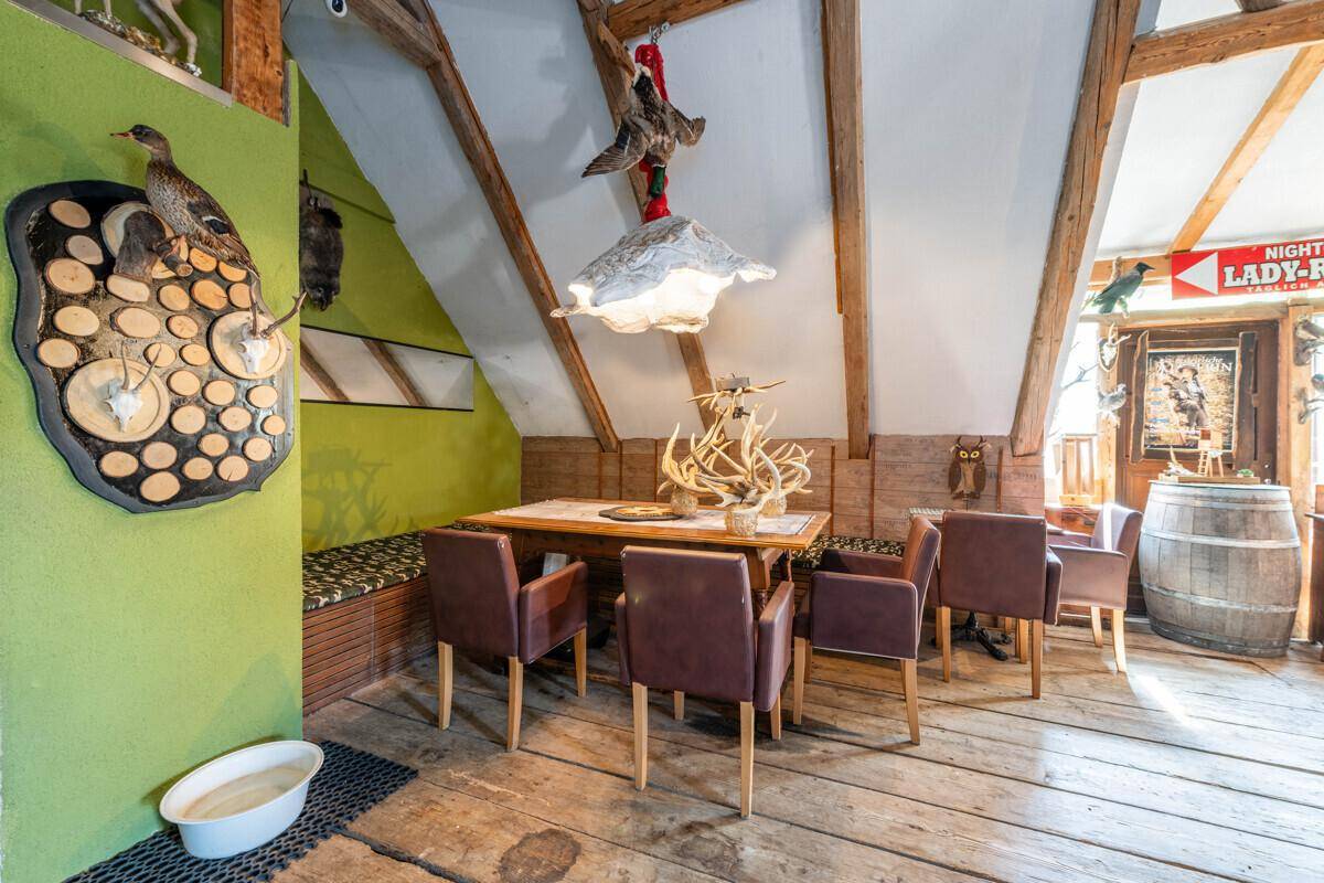 Detailansicht des rustikalen Essbereichs mit Holzbalken und traditionellen Jagdtrophäen.