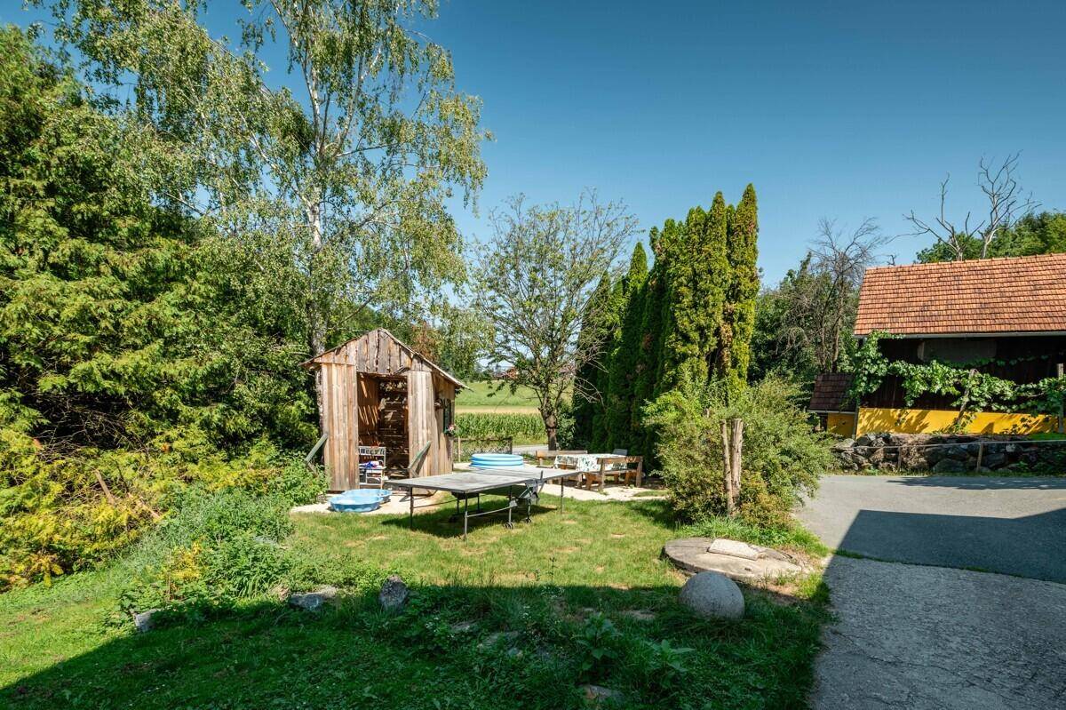 Idyllischer Gartenbereich mit Holzschuppen, Sitzgelegenheiten und einem kleinen Planschbecken.