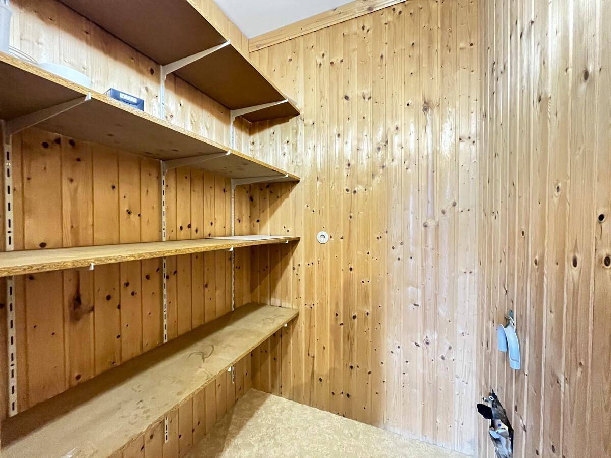 Praktischer Abstellraum mit Holzverkleidung und mehreren Regalböden für zusätzlichen Stauraum.