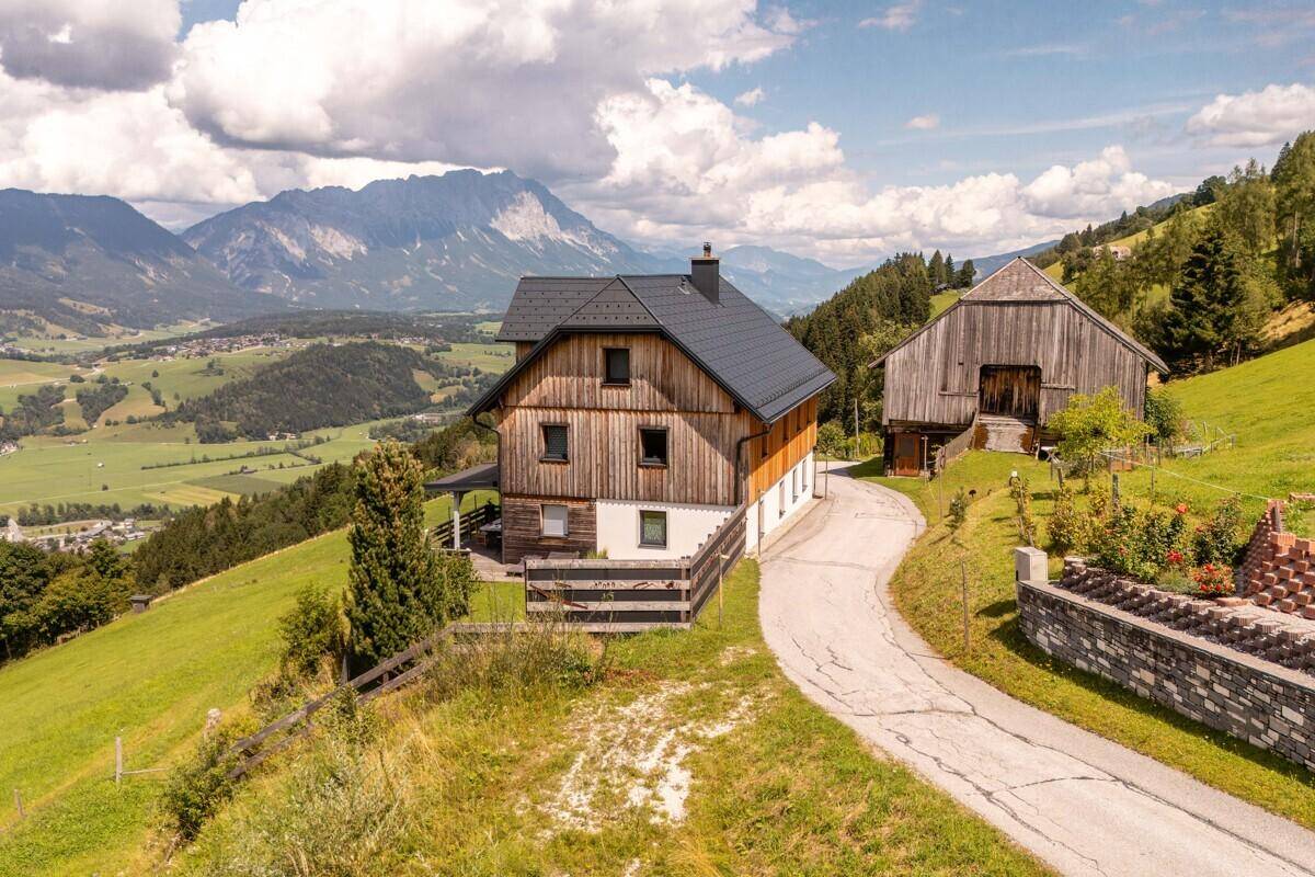 Idyllisches Anwesen mit Haupthaus und Scheune, eingebettet in eine malerische Berglandschaft.