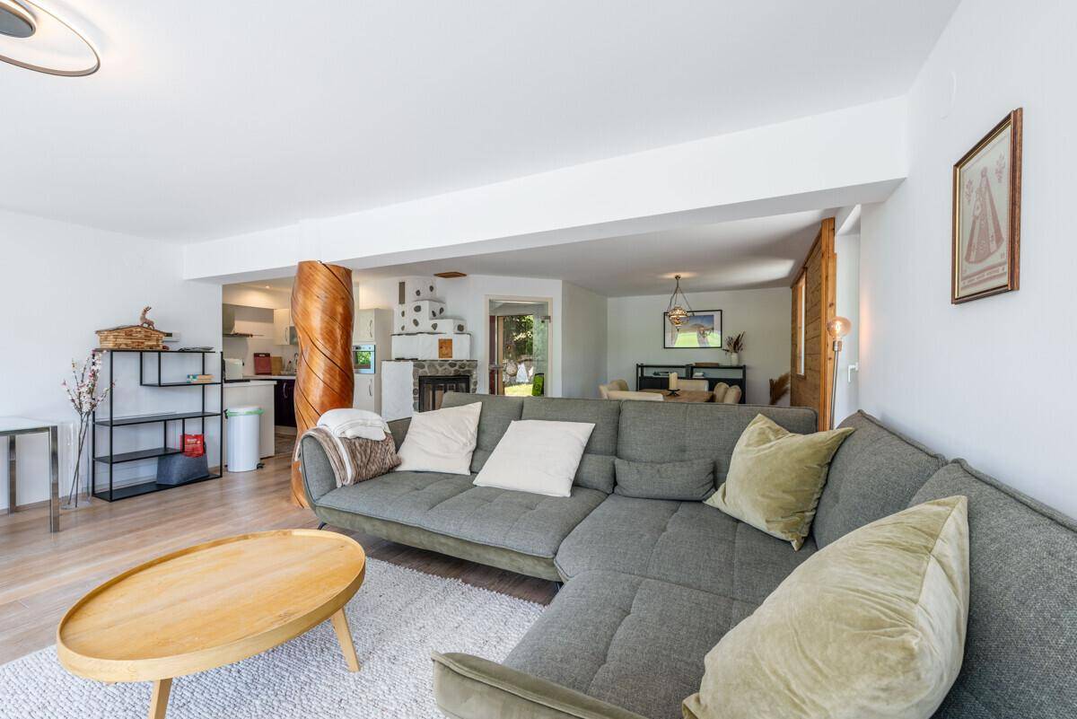 Offener Wohnbereich mit Sofa, Blick auf Küche und Essbereich, mit Kachelofen.