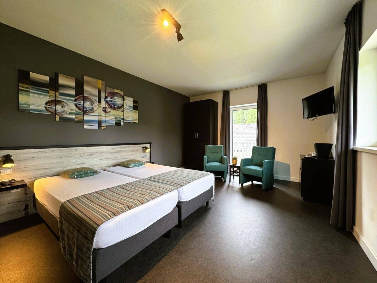 Geräumiges Schlafzimmer mit zwei Einzelbetten, dunklem Boden und Wandfernseher.