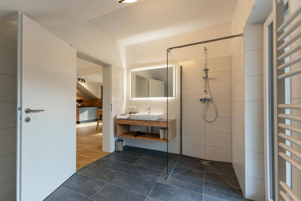 Modernes Badezimmer mit ebenerdiger Dusche, stilvollem Waschtisch und Fliesenboden.
