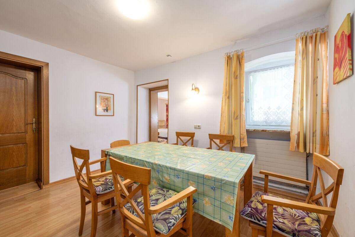 Heller Essbereich mit Holztisch und Stühlen, umgeben von weißen Wänden und Laminatboden.