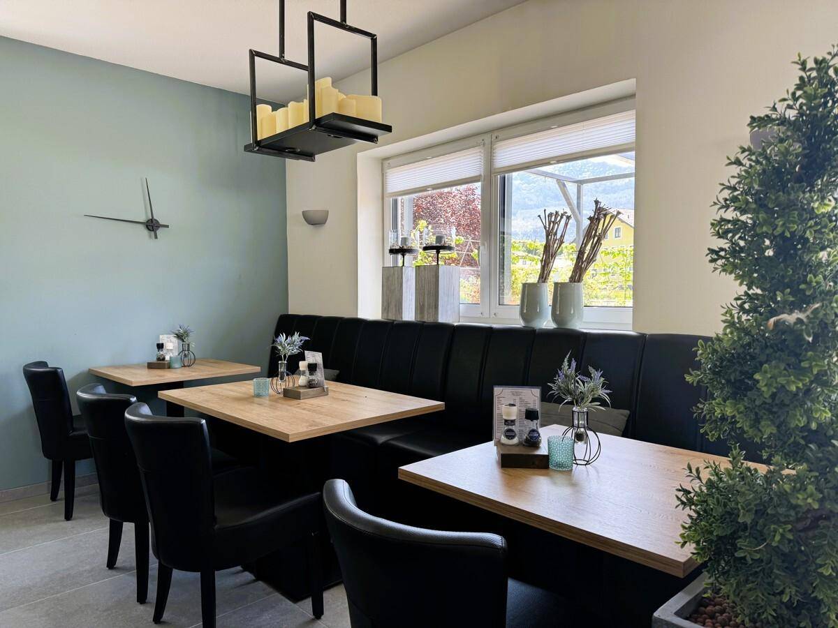 Essbereich mit Sitzbänken, Holztischen und Blick ins Grüne, modern gestaltet.