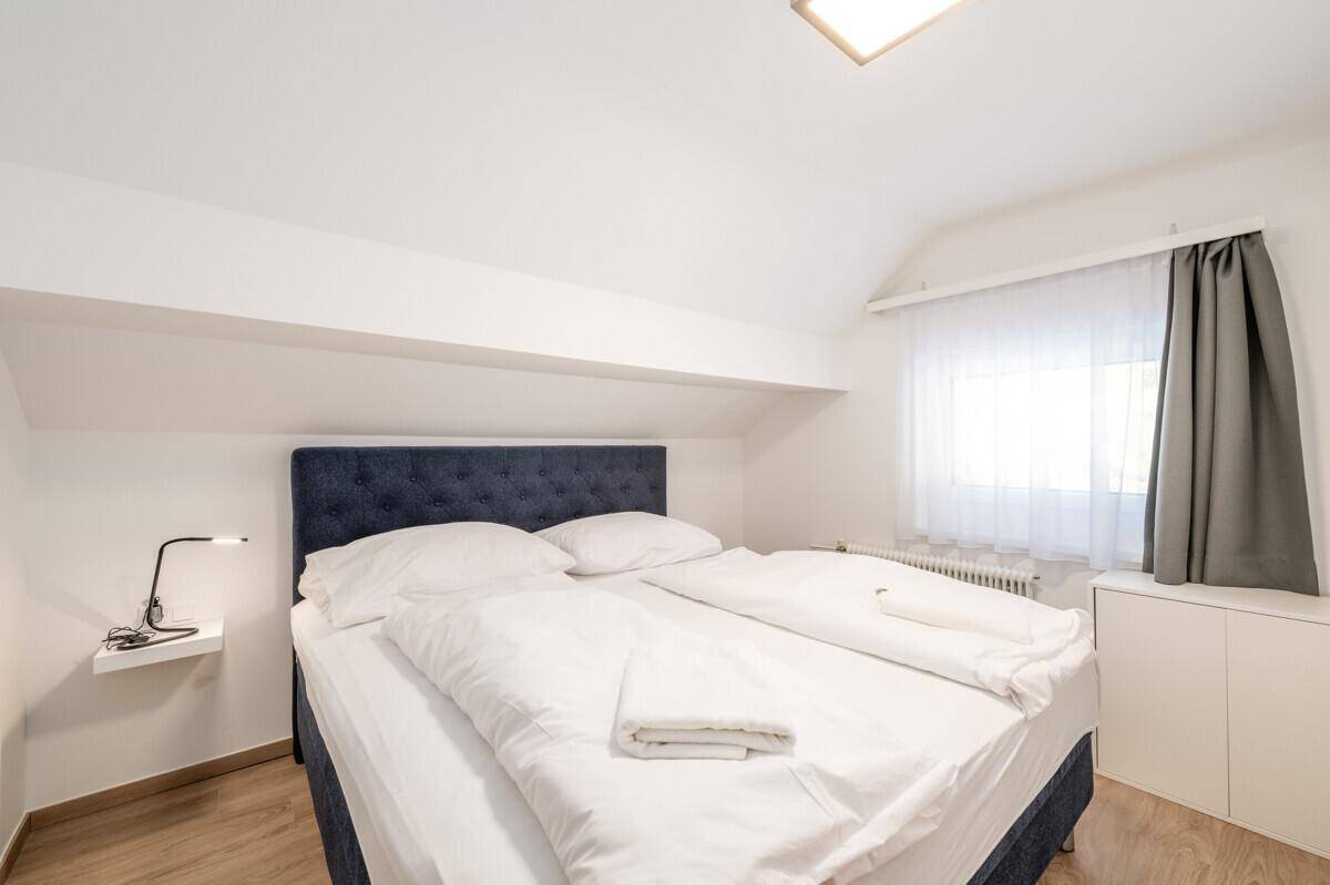Gemütliches Schlafzimmer im Dachgeschoss mit Doppelbett und schräger Decke.