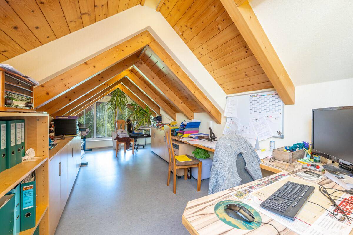 Geräumiges Dachgeschoss-Büro mit Holzbalken, viel Stauraum und Blick ins Grüne.