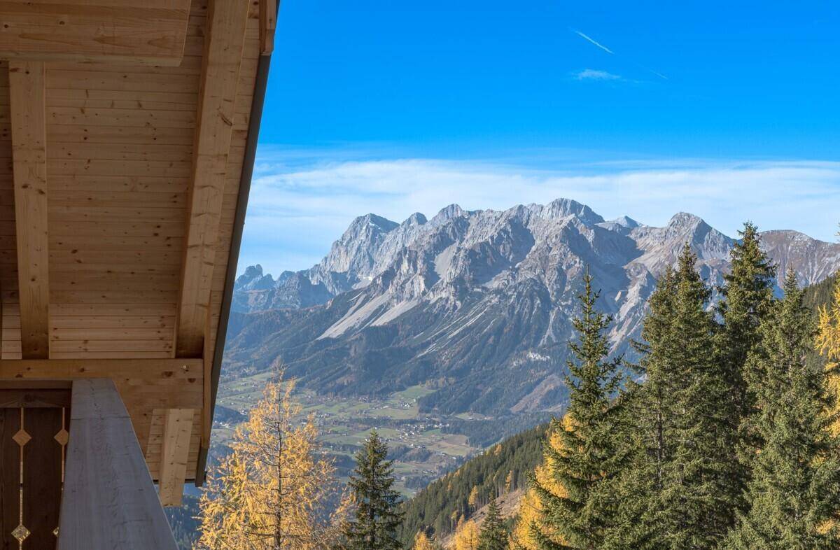 Spektakulärer Bergblick von der Unterkunft mit grünen Tannen und herbstlichen Bäumen.