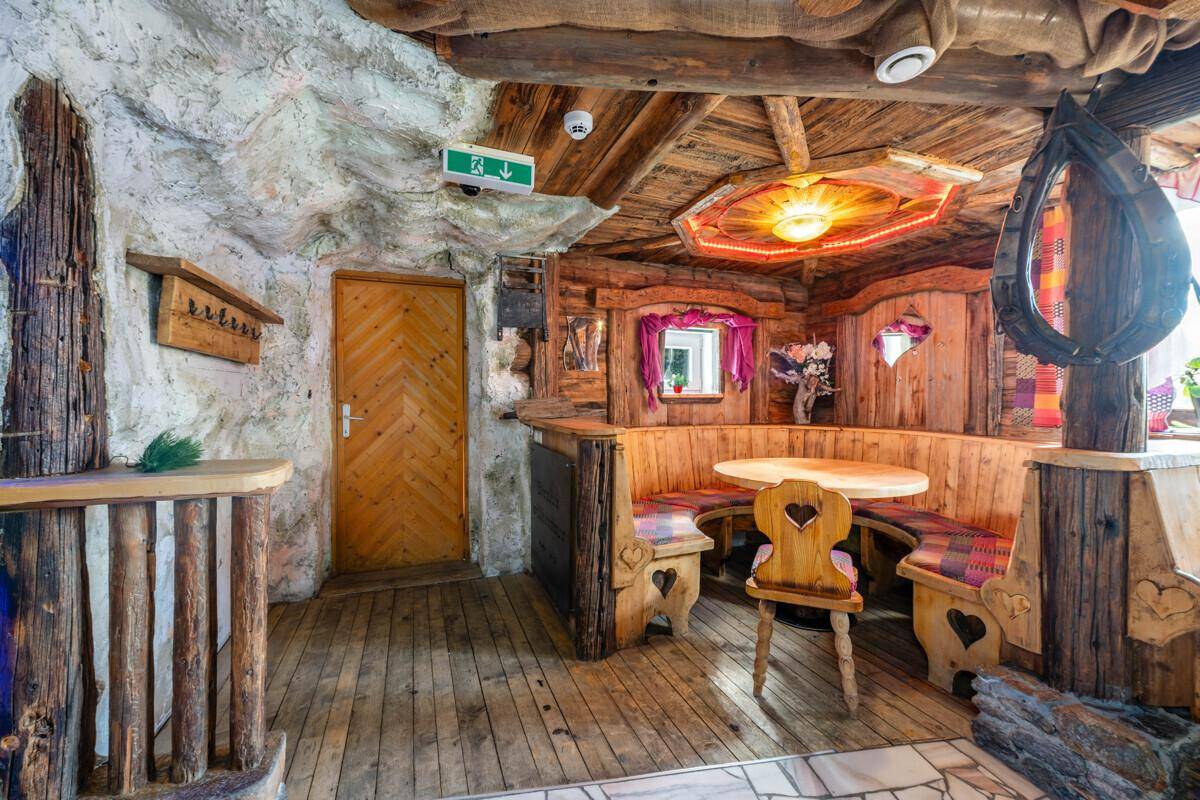 Rustikaler Innenraum mit geschnitztem Holz, steinähnlichen Wänden und einer gemütlichen Sitzecke.