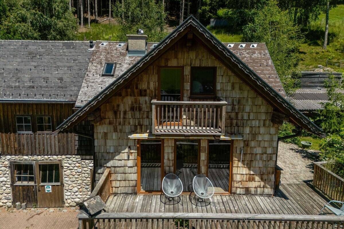 Detailansicht der Holzfassade eines Chalets mit Balkon und möblierter Terrasse.