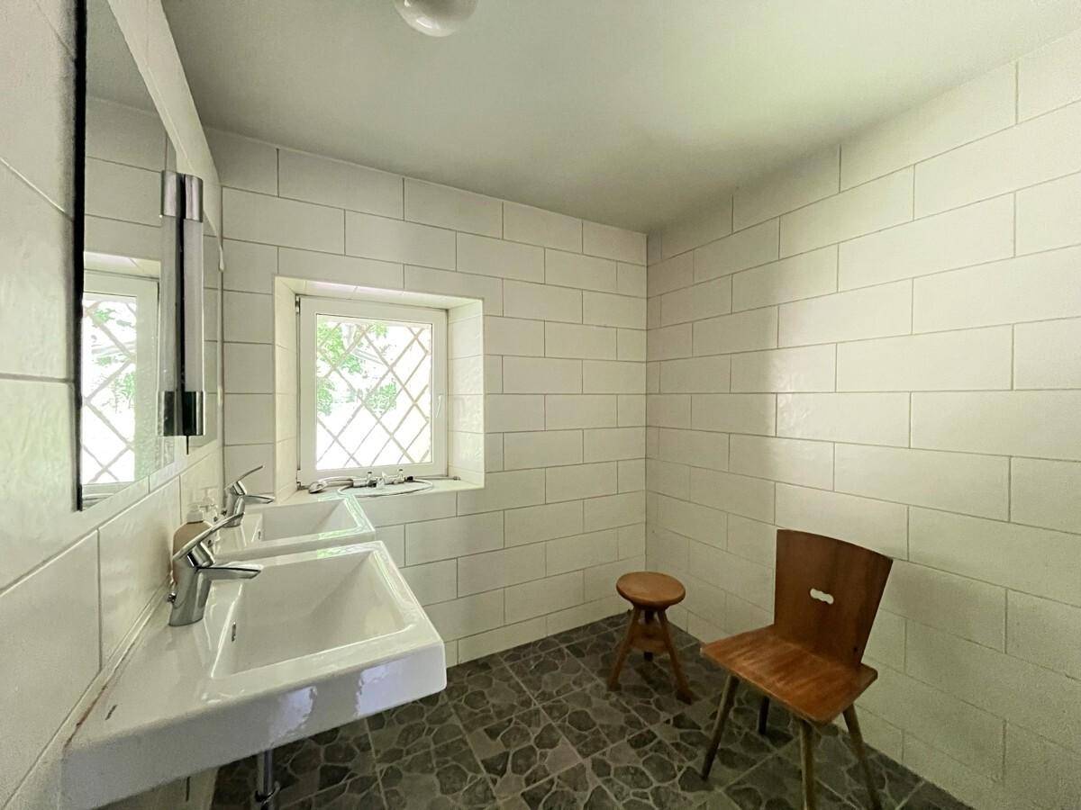 Modernisiertes Badezimmer mit Doppelwaschbecken, weißen Fliesen und Fenster.