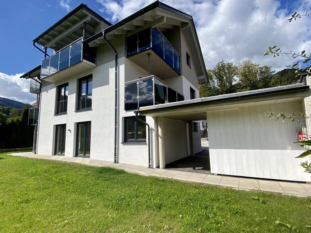 Neubau mit moderner Architektur, Balkonen und Carport in grüner Umgebung.
