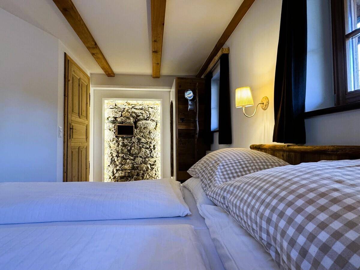 Schlafzimmer mit bequemen Betten und einem beleuchteten Durchgang zu einer rustikalen Steinwand.
