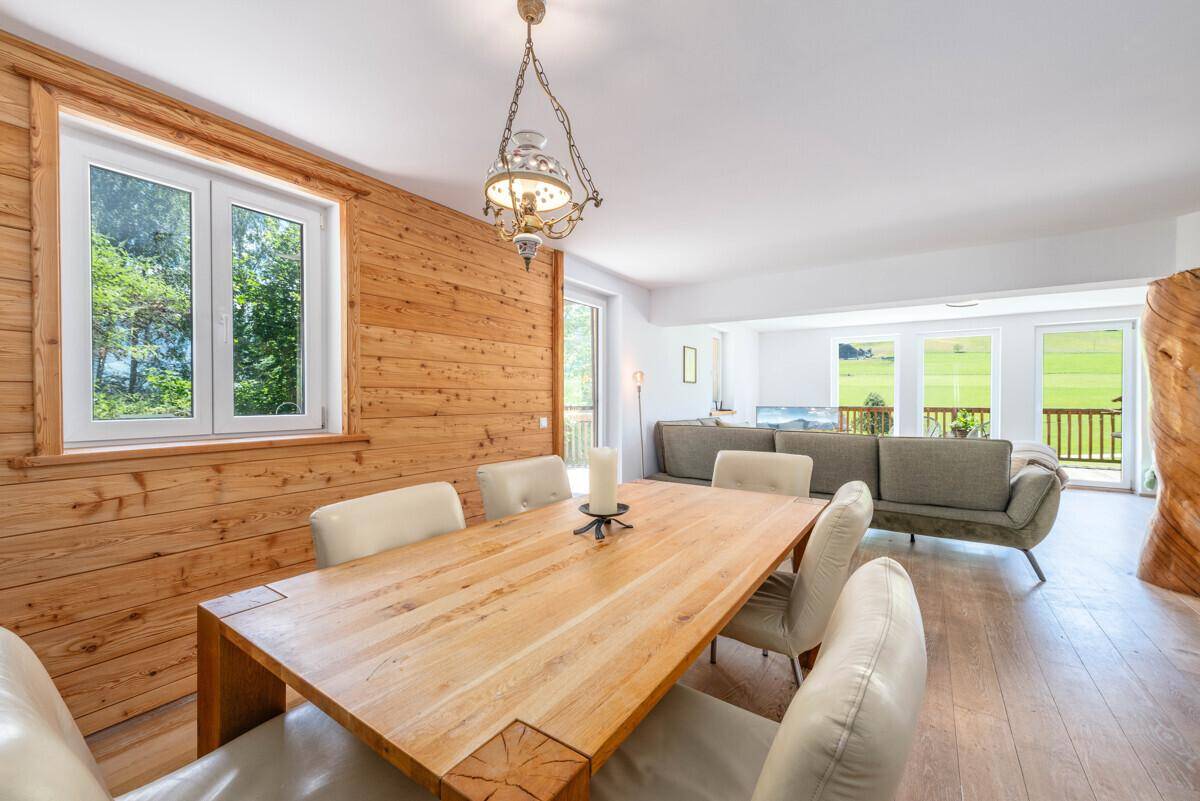 Essbereich mit Holztisch und Stühlen, Holzwand und offenem Blick zum Wohnzimmer.