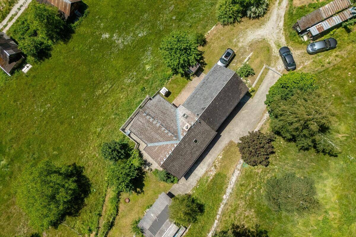 Senkrechte Luftaufnahme des Chalets mit Satteldach, umgeben von Rasenflächen und einer Zufahrt.