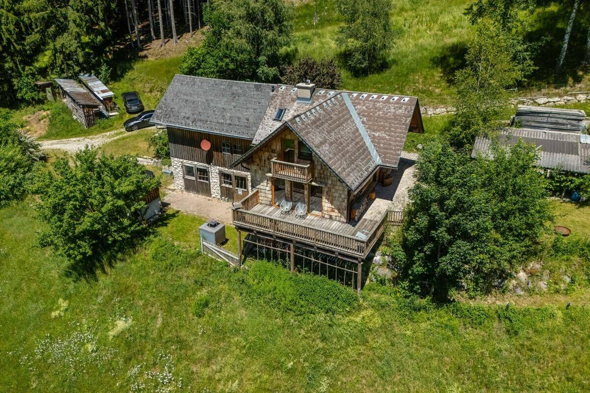Das Chalet mit seiner großen Holzterrasse ist harmonisch in die grüne, bewaldete Umgebung eingebettet.