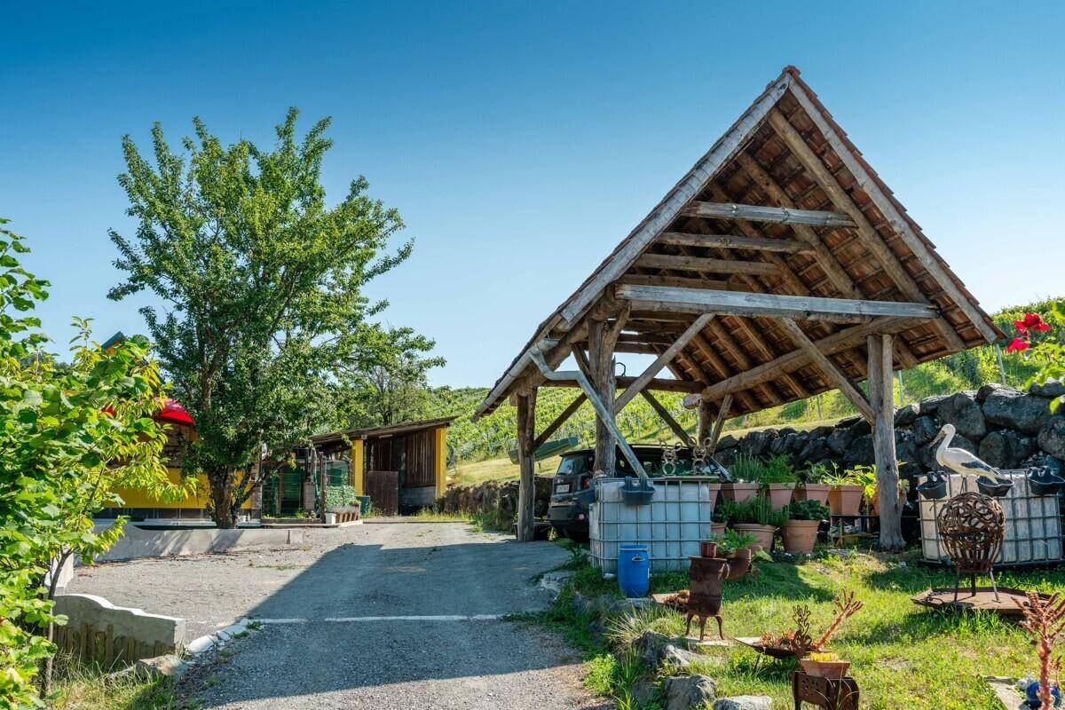 Holz-Carport mit Gartenbereich und verschiedenen Pflanzen und Dekorationen.