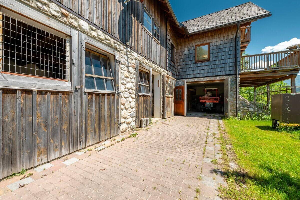 Rustikales Gebäude mit Stein- und Holzfassade, gepflasterter Auffahrt und offener Garage.