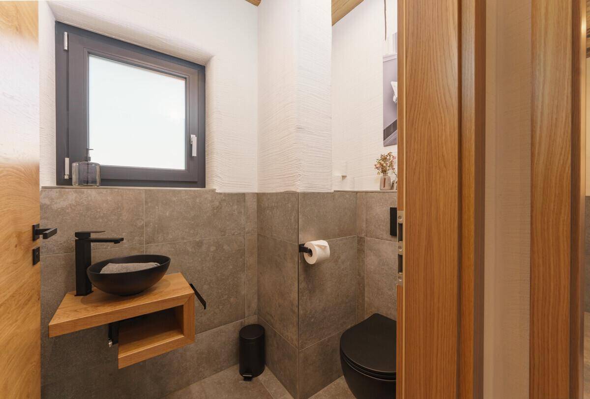 Modernes Gäste-WC mit Fenster, schwarzer Toilette und Aufsatzwaschbecken.