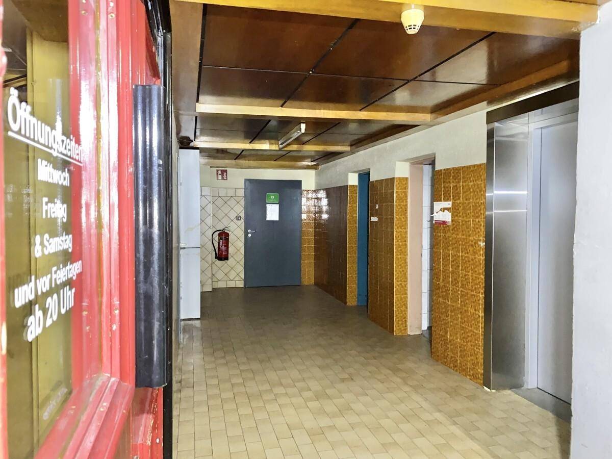 Flur oder Gemeinschaftsbereich mit gefliestem Boden, holzgetäfelter Decke und einem Aufzug.