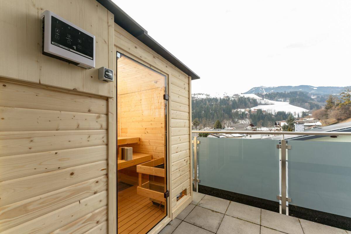 Private Außensauna auf der Terrasse mit Panoramablick auf die verschneiten Berge.