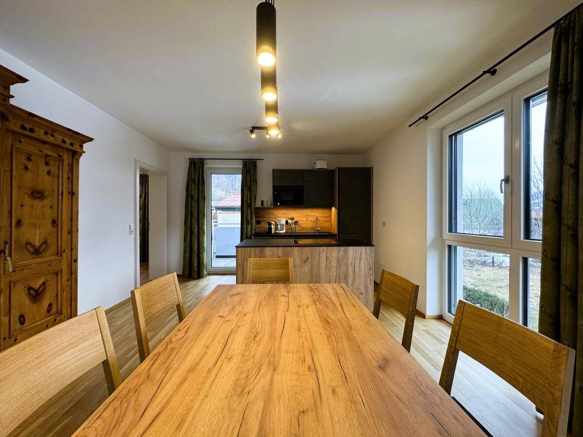 Heller Essbereich mit Holztisch, modernen Pendelleuchten und Blick auf die offene Küche.