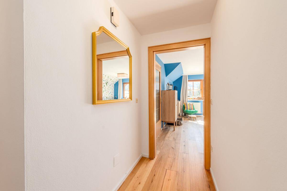 Heller Flur mit Holzboden und einem dekorativen Spiegel an der Wand.