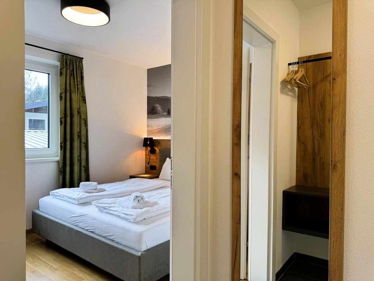Flur mit Blick in ein helles Schlafzimmer und offener Garderobe.
