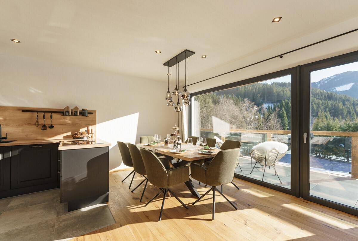 Heller Wohn- und Essbereich mit Holzboden, großem Esstisch und Bergblick.