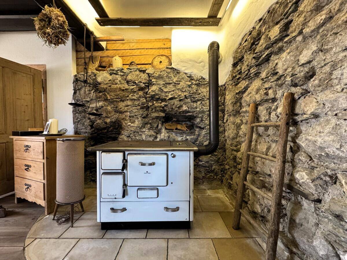 Wohnbereich mit traditionellem Holzofen und beeindruckender Natursteinwand, die rustikalen Charme verleiht.