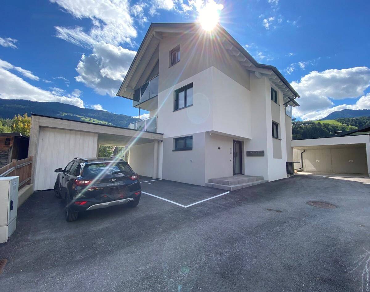 Modernes Wohnhaus mit Carport und gepflasterter Auffahrt in sonniger Berglage.