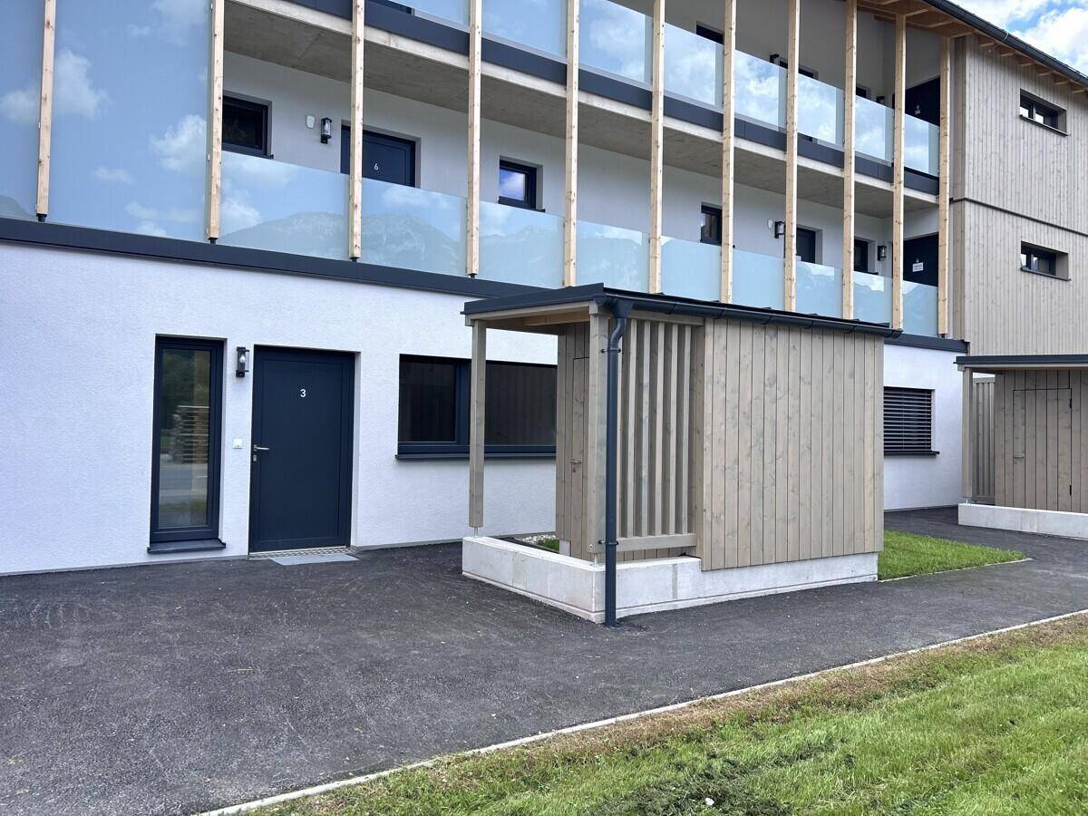 Moderne Gebäudefassade mit Holzelementen, Balkonen und Eingangsbereich.